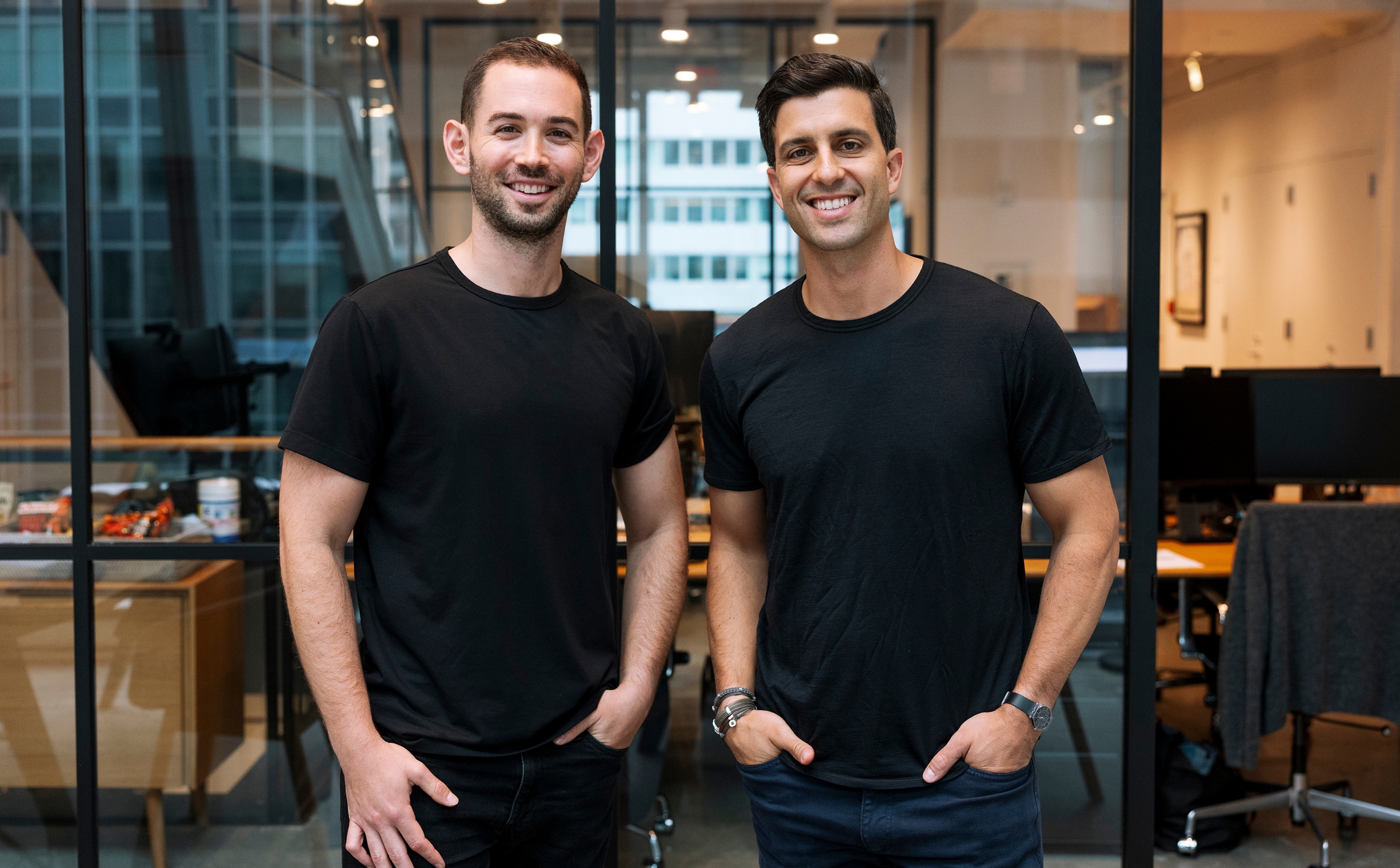 Two men standing and smiling in an office setting with glass walls, Mike Berlin and Isaac Harrouche - 154 Partner CEOs